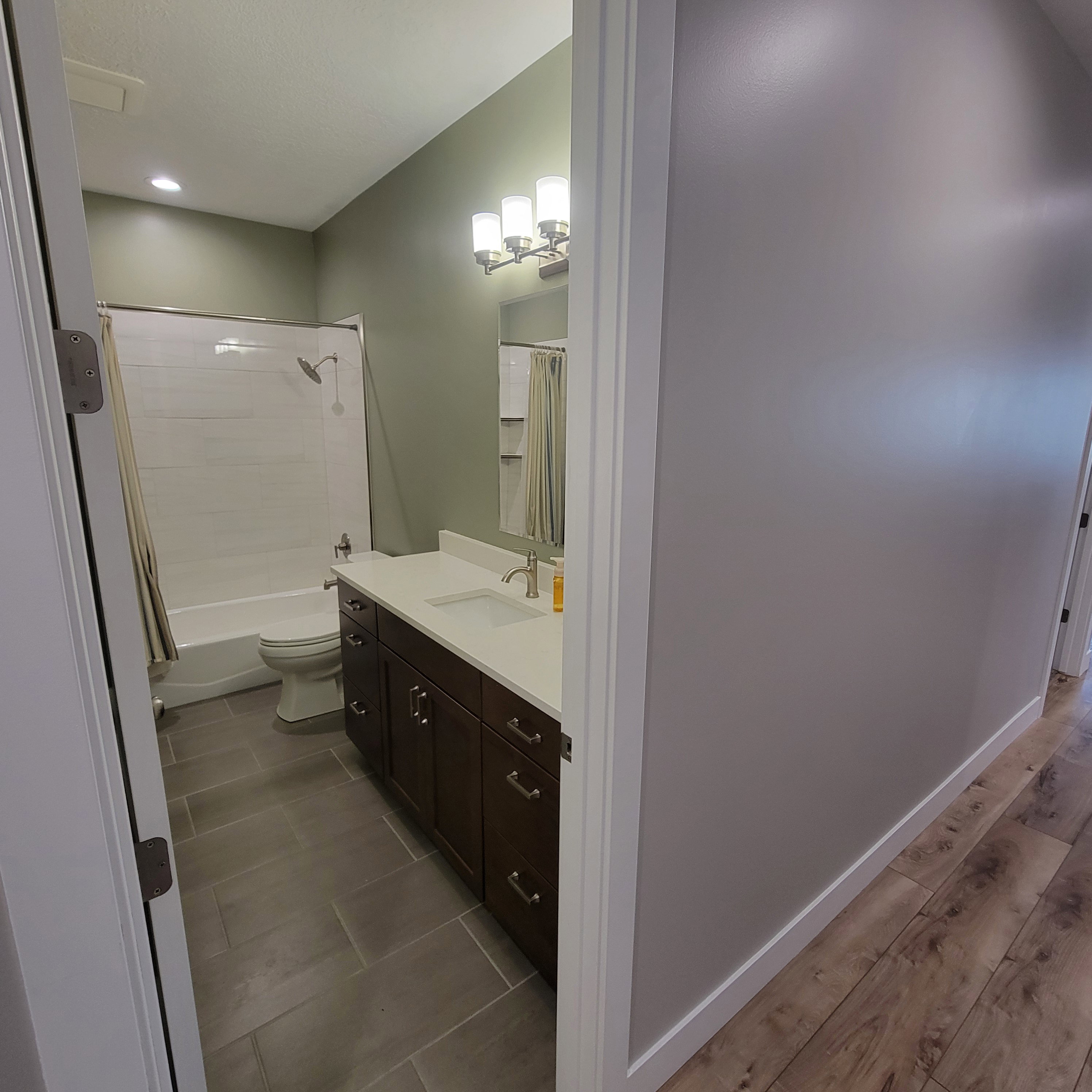 Full bathroom featuring a dark wood-finish vanity with a white countertop, undermount sink, and brushed nickel faucet
