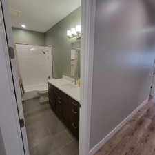 Full bathroom featuring a dark wood-finish vanity with a white countertop, undermount sink, and brushed nickel faucet