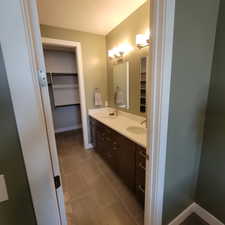 Bathroom featuring dual vanity with brown cabinetry, light-toned countertops, and two undermount sinks