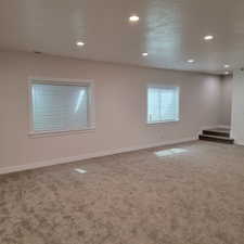 Spacious room featuring neutral carpeting, light-toned walls, and recessed ceiling lighting