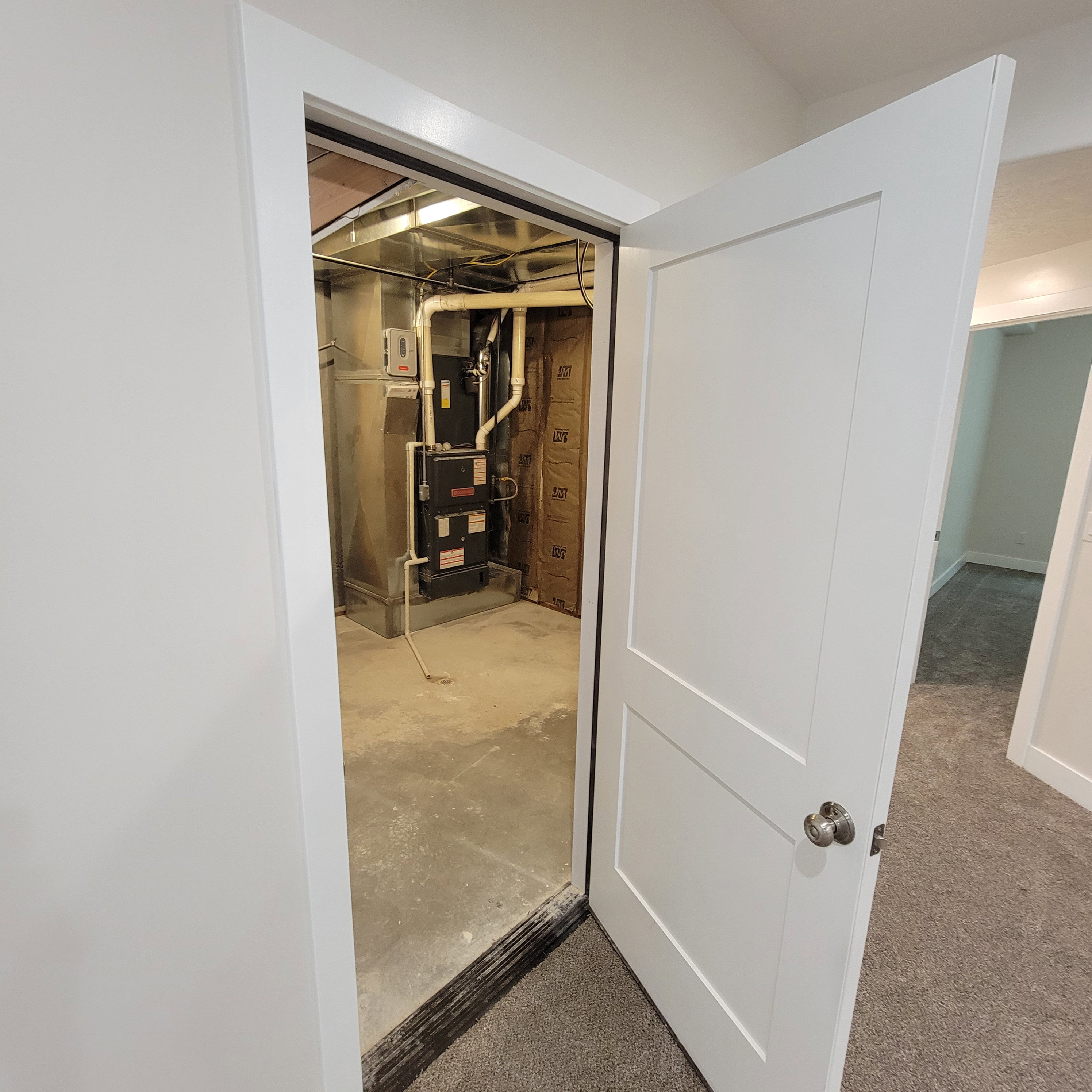 Utility room featuring a furnace system with exposed ductwork, concrete flooring, and insulated walls