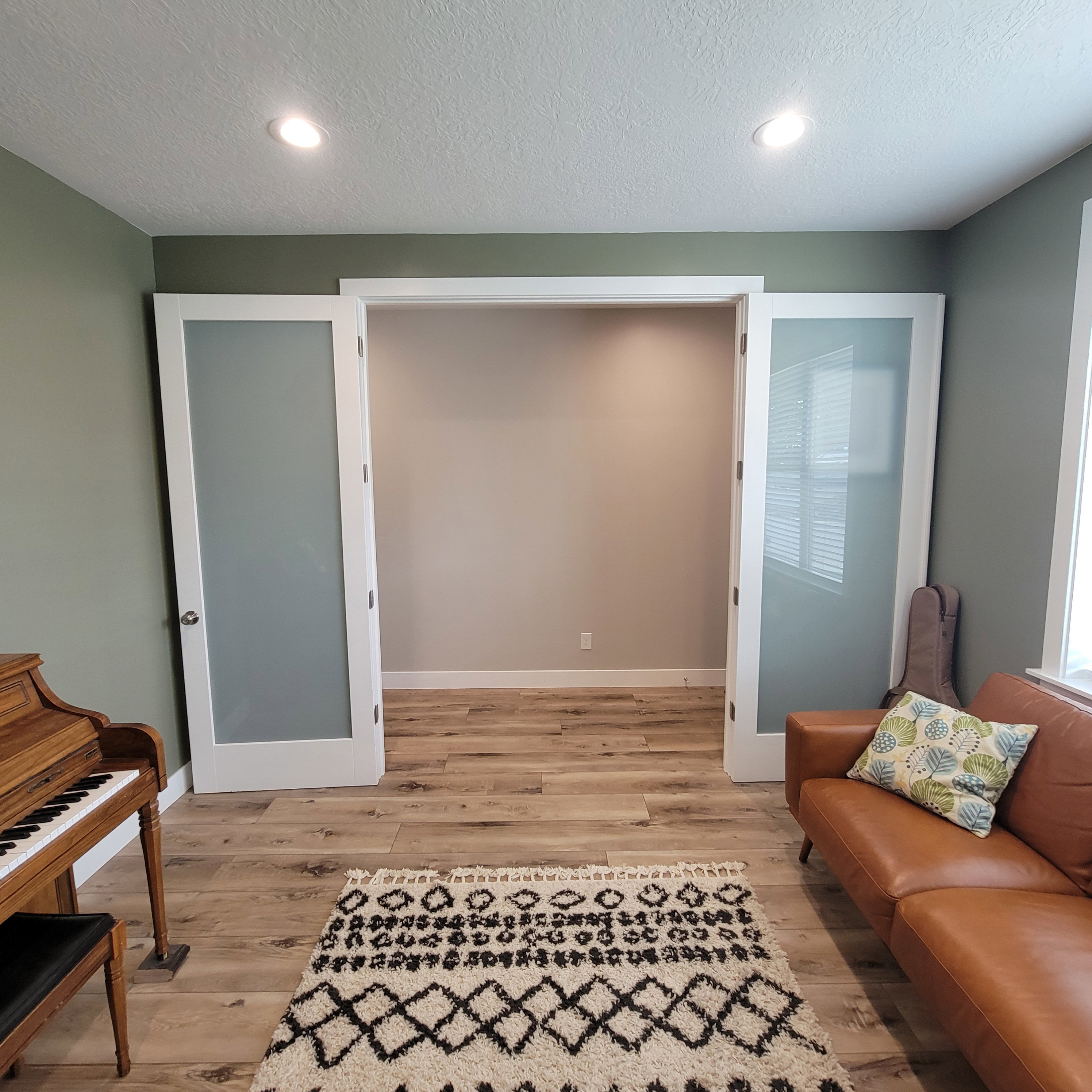 Frosted glass French doors opening to an interior room with wood-finish flooring