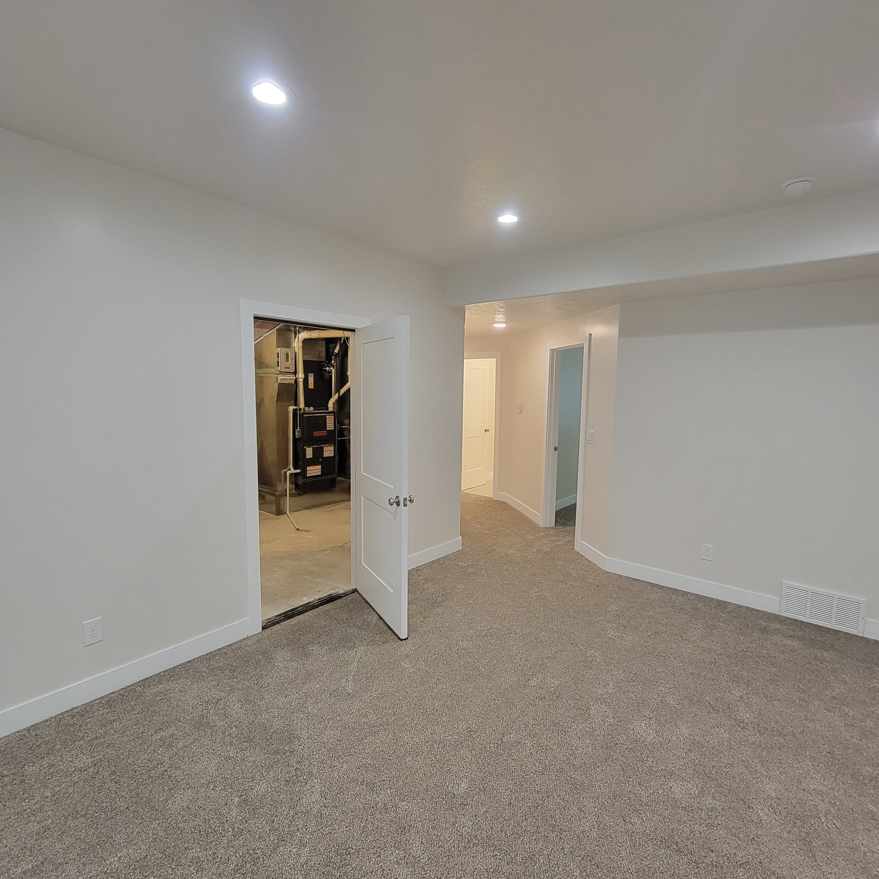 Spacious room featuring new carpeting, recessed lighting, white walls, white trim, and a white interior door