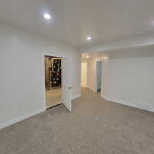 Spacious room featuring new carpeting, recessed lighting, white walls, white trim, and a white interior door