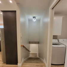 Stairwell featuring a contemporary ceiling-mounted light fixture, light gray walls, a wood handrail, and carpeted steps