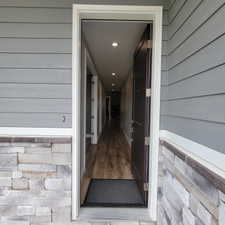 Entryway featuring a dark paneled door, wood-finish flooring, and recessed ceiling lighting