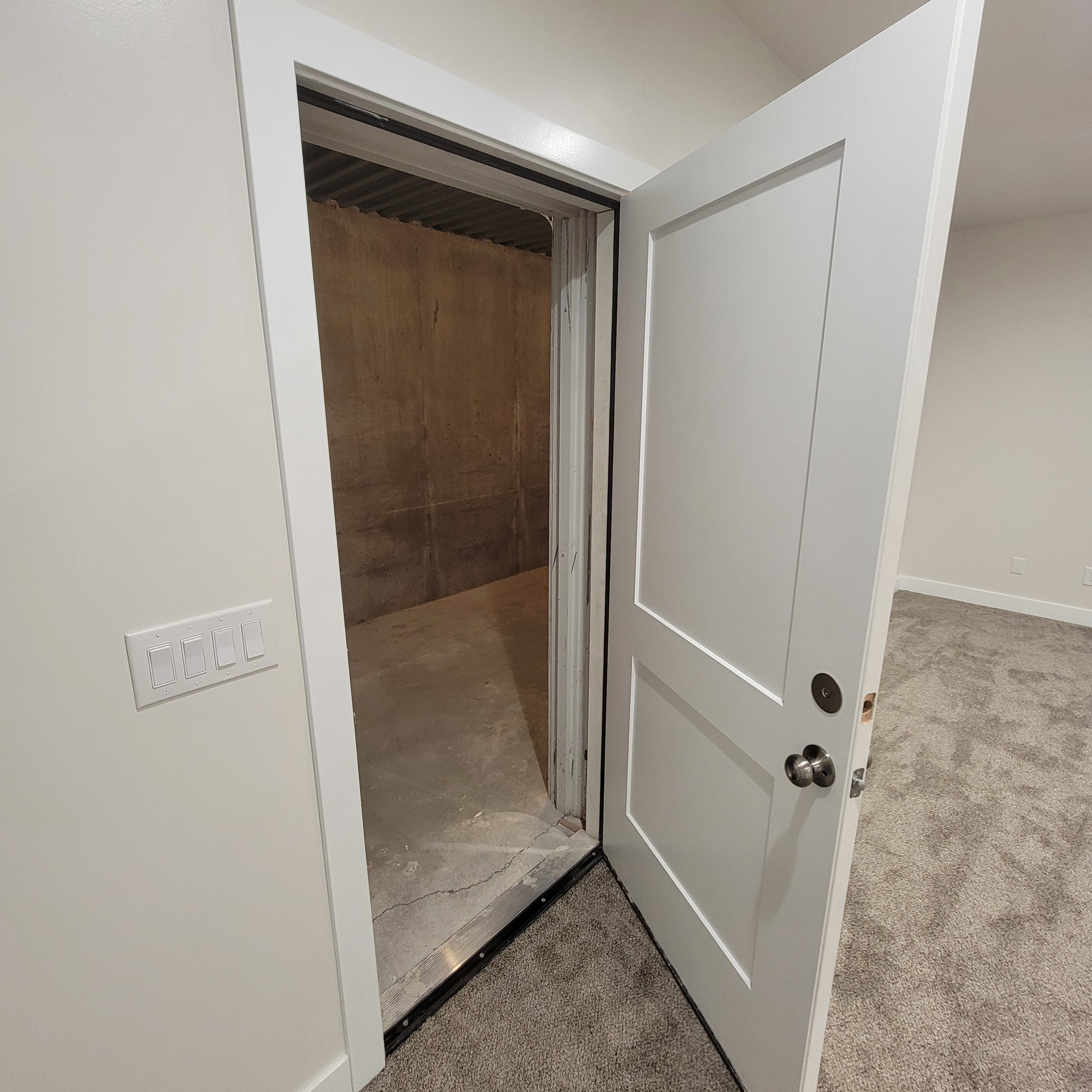 Solid-core door revealing a concrete-floored space with concrete walls