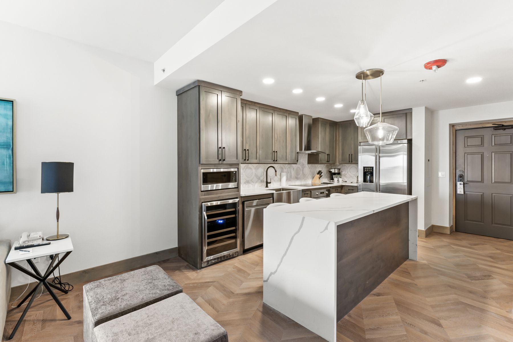 Modern kitchen featuring gray cabinetry, stainless steel appliances, and a waterfall island with a quartz countertop