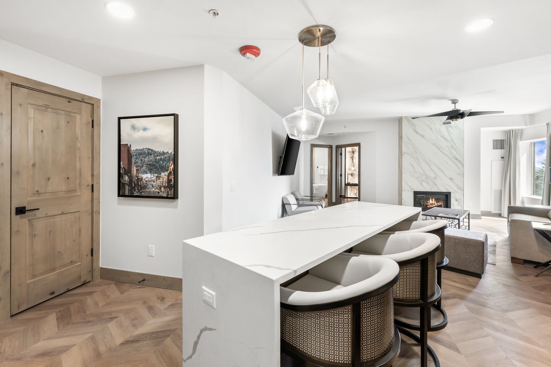 Kitchen island with a waterfall countertop and integrated seating, illuminated by a multi-pendant fixture