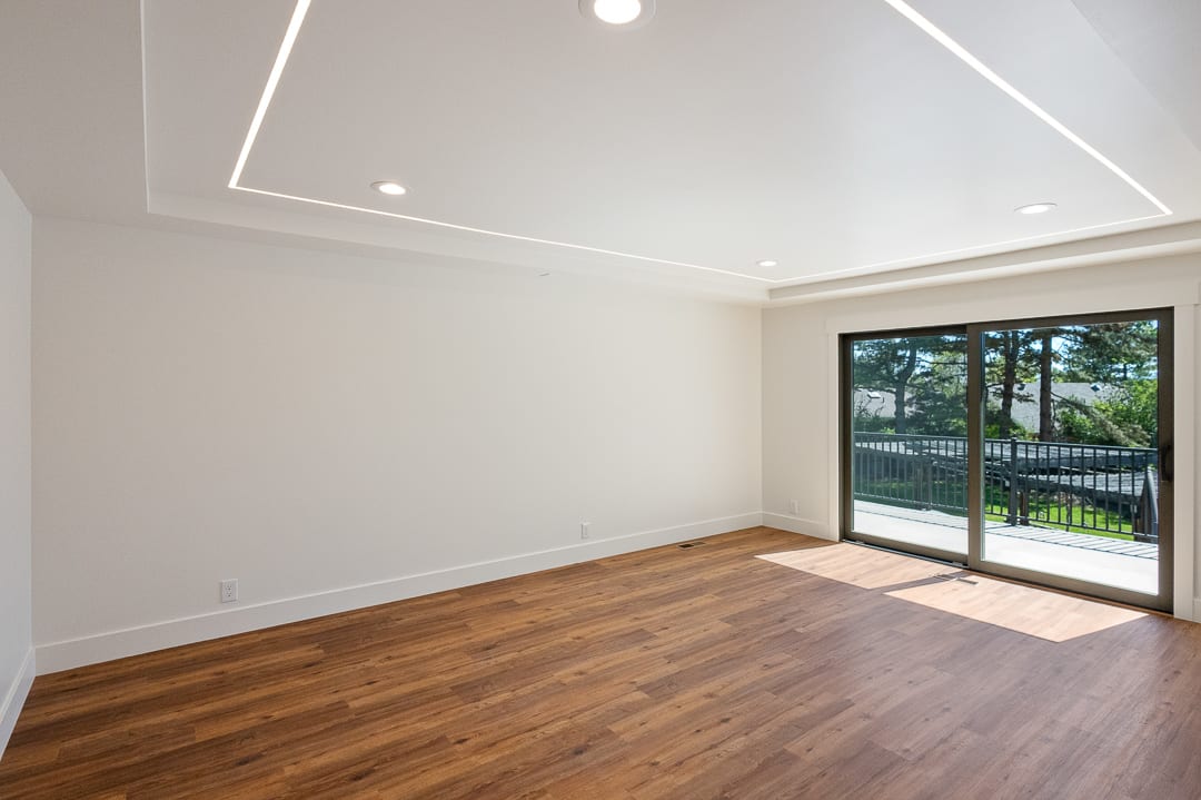 Spacious room featuring wood-finish flooring, white walls, and a recessed ceiling with integrated lighting