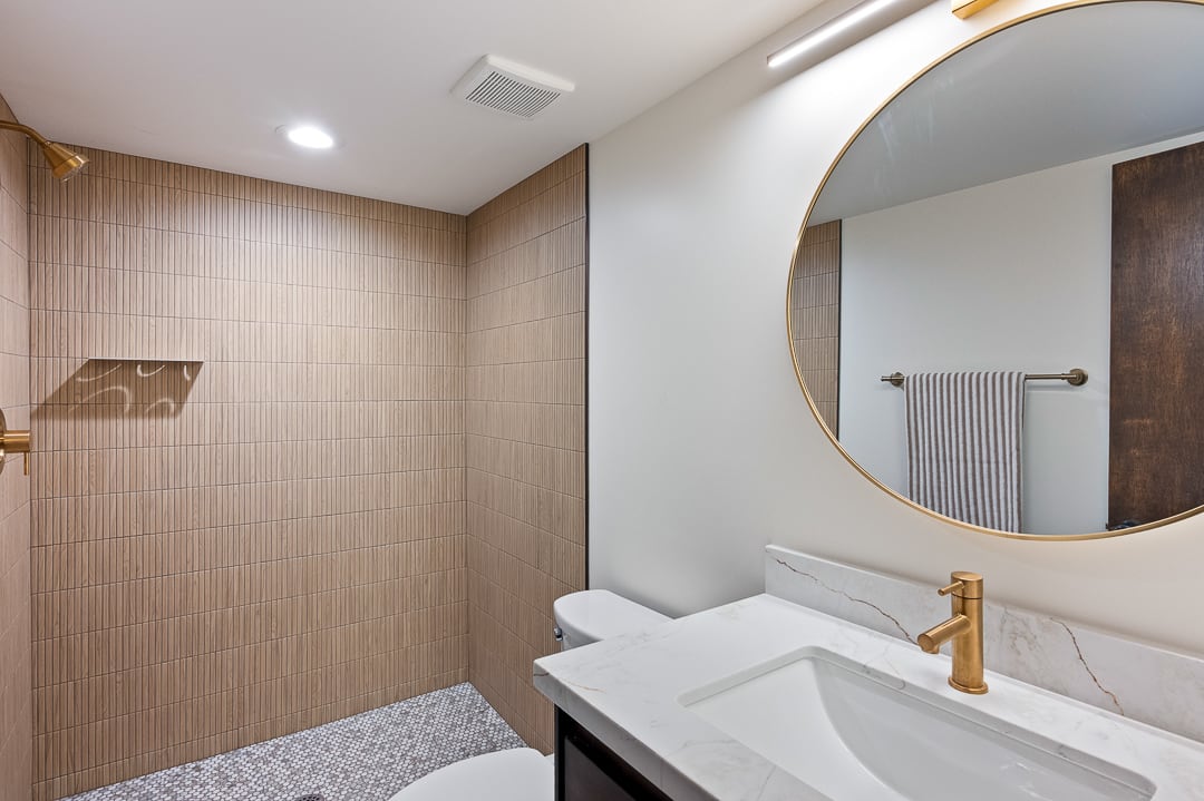 Bathroom featuring a walk-in shower with textured tile walls, a built-in shower niche, and pebbled flooring