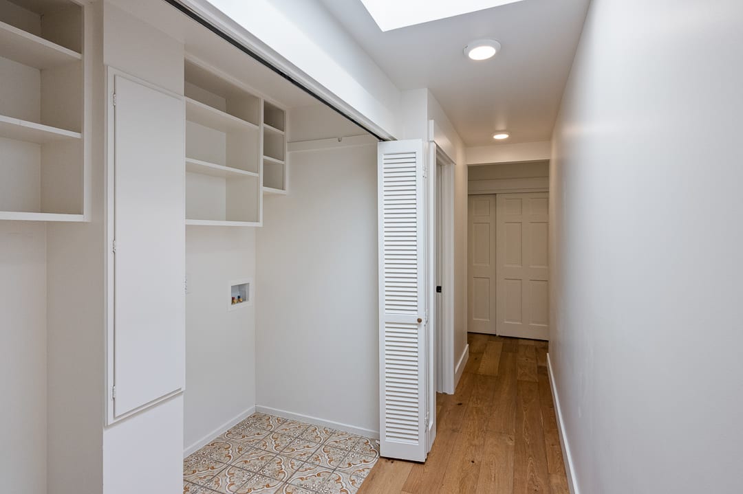 Laundry area featuring patterned floor tile, built-in shelving, and a skylight