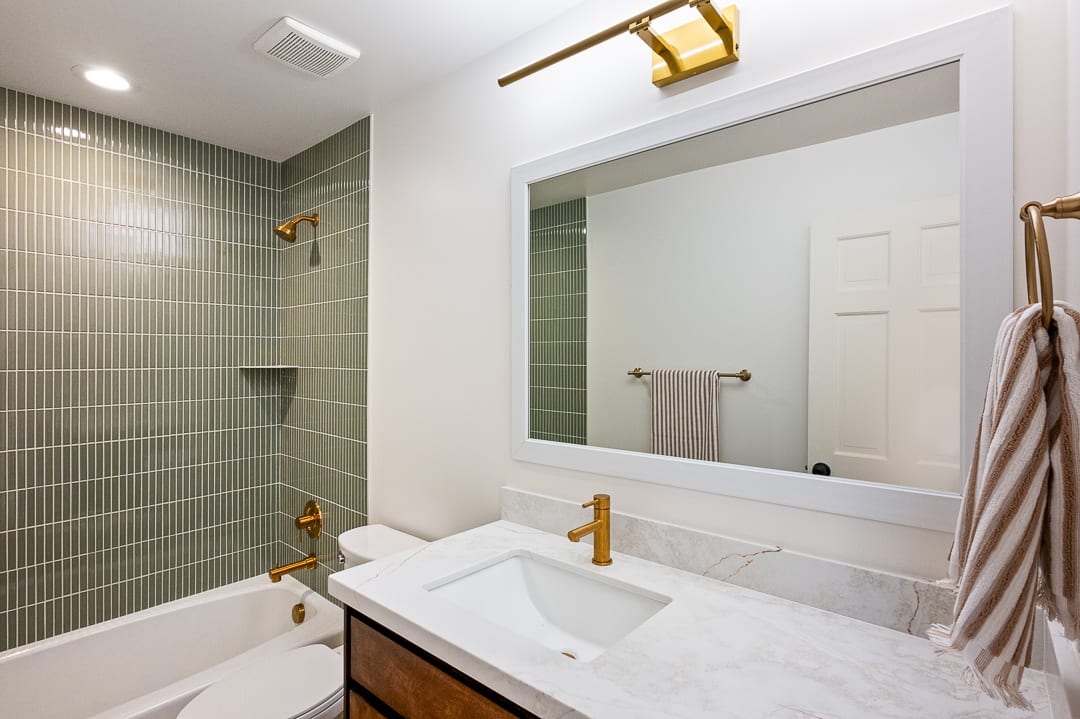 Bathroom vanity with a white framed mirror, gold-finish hardware, and a white countertop