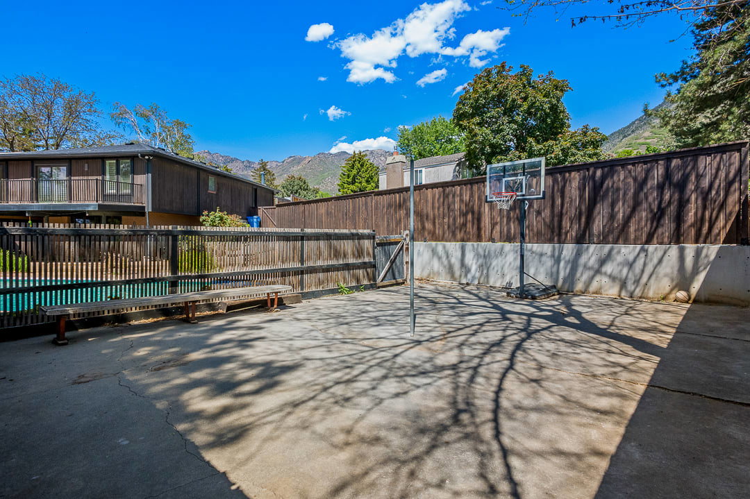 Concrete patio featuring a privacy fence, an adjacent swimming pool, and a mountain backdrop
