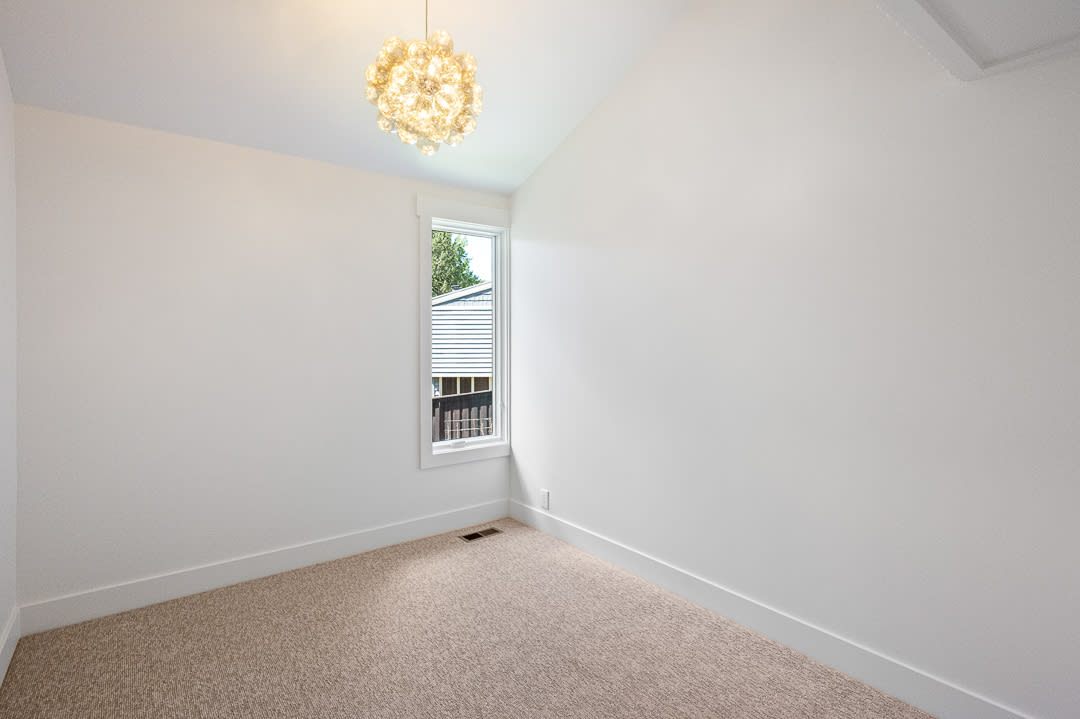 Vaulted ceiling room featuring a contemporary light fixture, single window, clean white walls, and neutral-toned carpeting