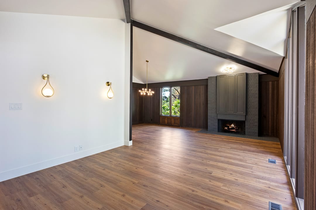 Spacious interior featuring wood-finish flooring, a contemporary fireplace with a paneled surround, and a vaulted ceiling with exposed beams