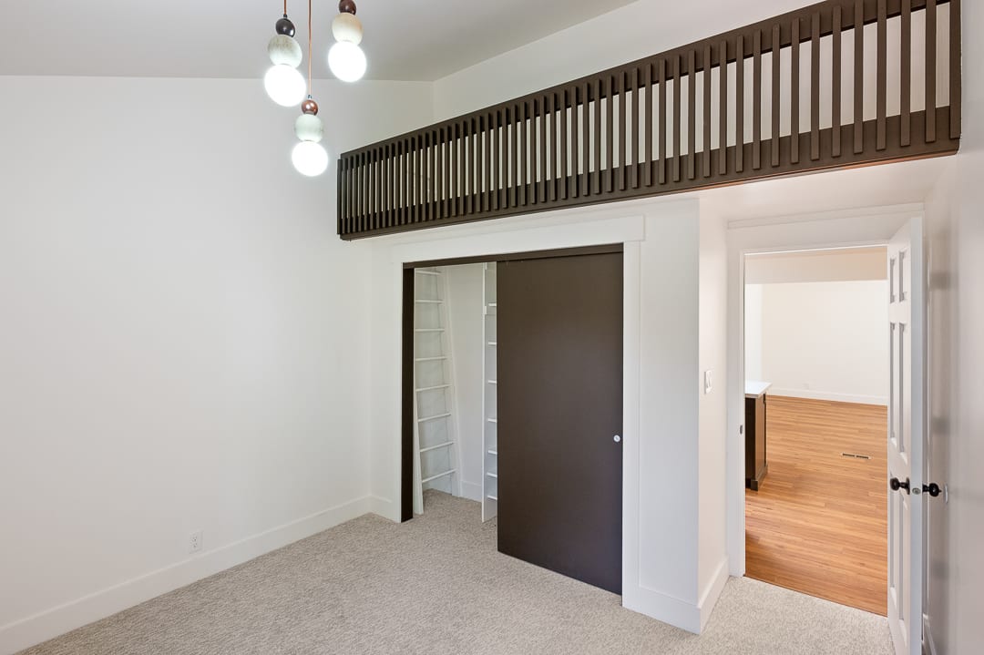 Carpeted room featuring a built-in loft structure with slat railing