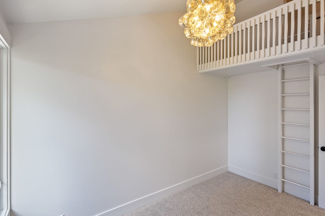 Loft space featuring a decorative light fixture, built-in ladder, and light-colored carpeting