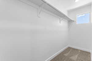 Walk-in closet featuring white walls, a single shelf with a hanging rod, recessed lighting, and a square window