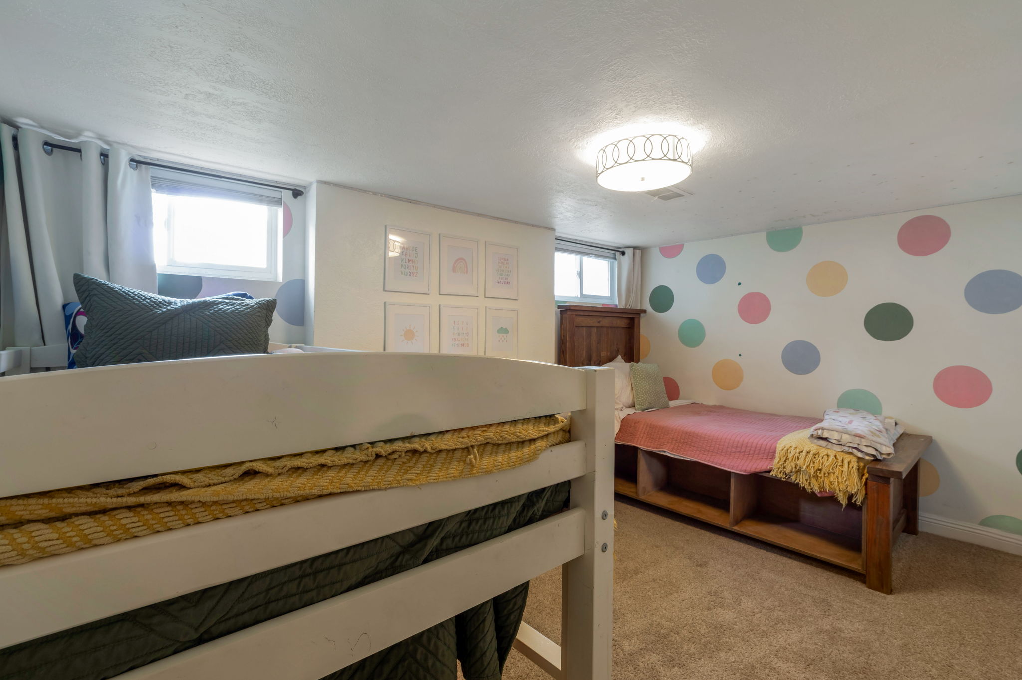 Carpeted room featuring a built-in bed frame with integrated shelving, a decorative accent wall, and a flush-mount ceiling light fixture