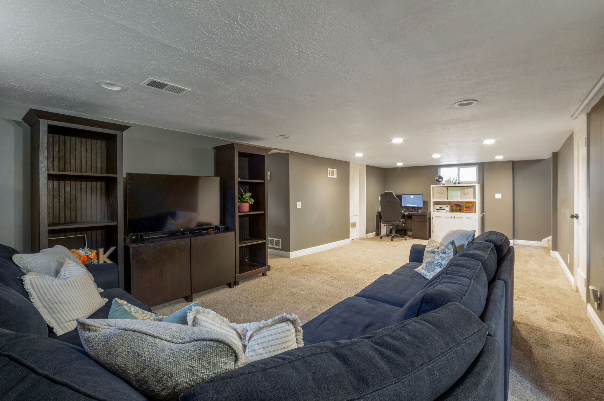 Spacious lower-level area featuring recessed lighting, a neutral carpeted floor, and painted walls