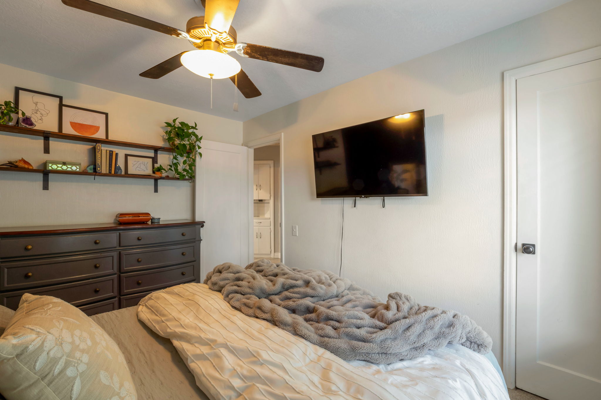 Interior room featuring a ceiling fan with integrated lighting, wall-mounted shelving, white interior doors, and neutral wall tones
