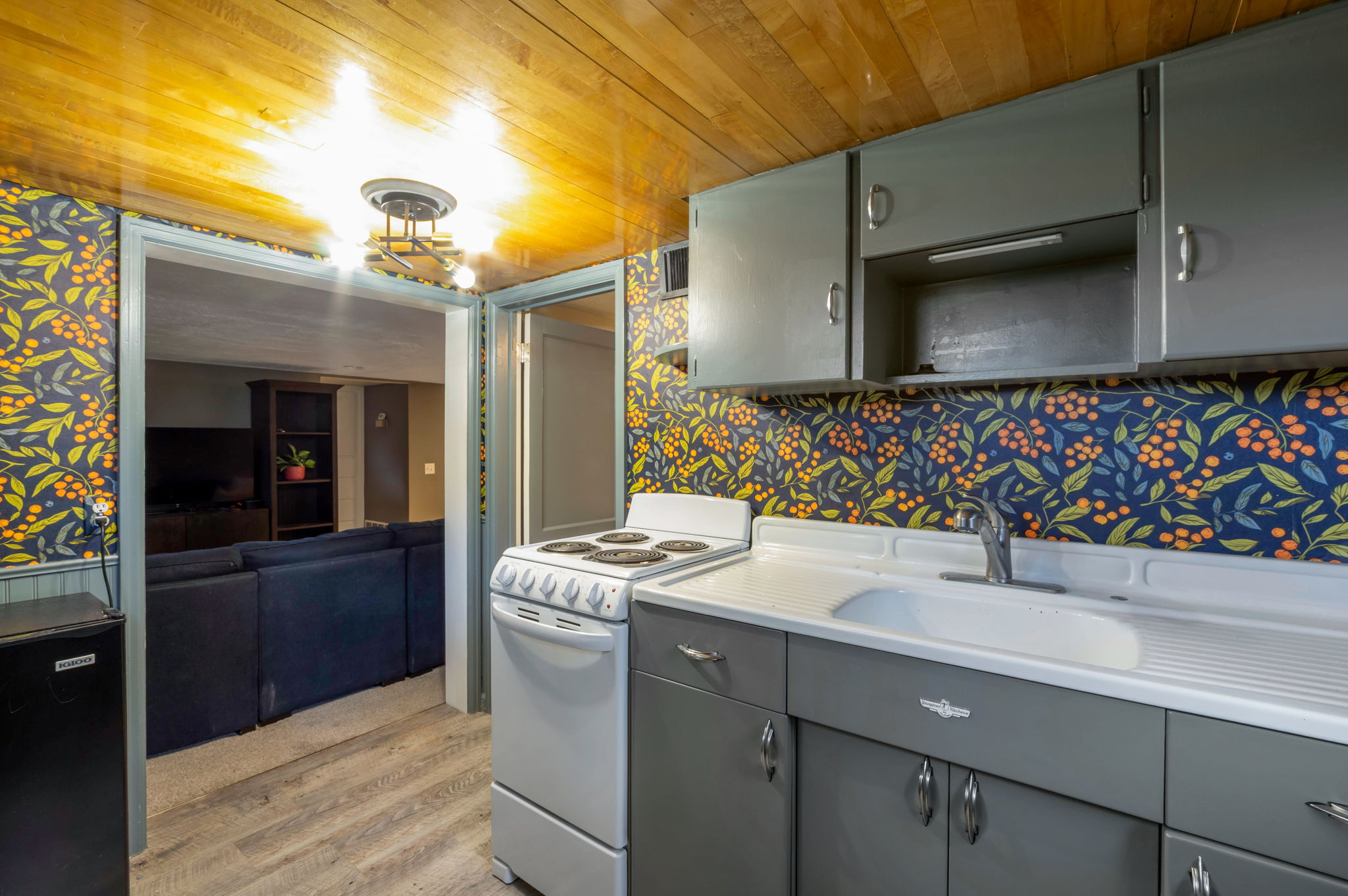 Kitchenette featuring grey cabinetry, a white electric range, and a single basin sink with a chrome faucet