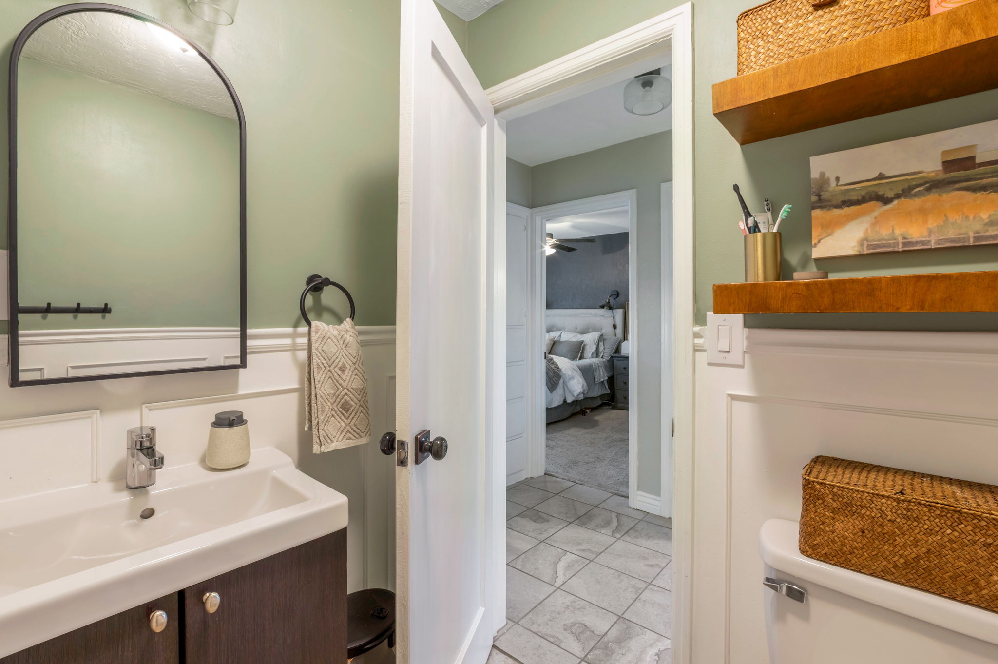 Bathroom featuring a white vanity with dark wood-finish cabinetry, a rectangular sink, and a black-framed arched mirror