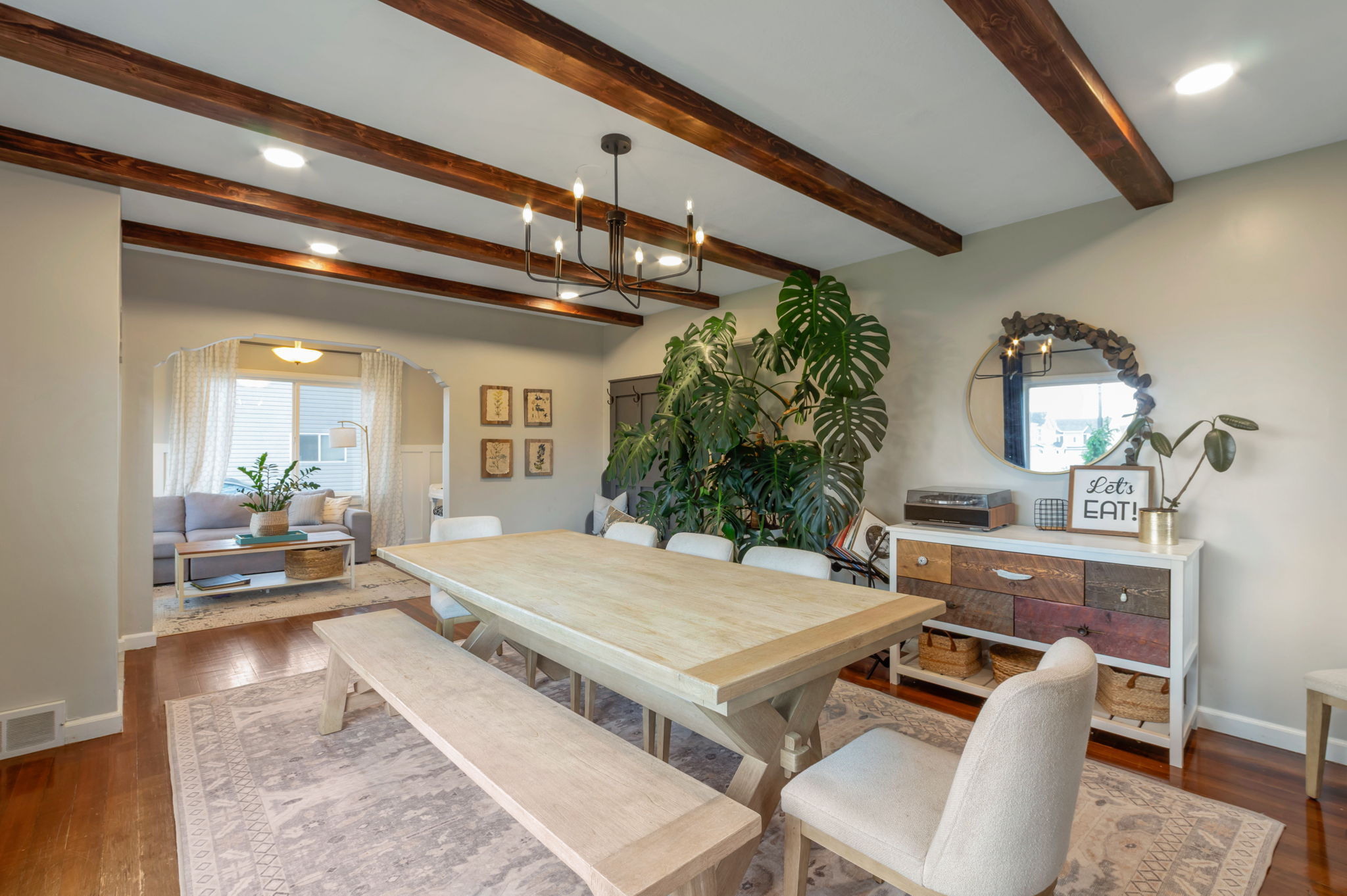 Dining area featuring wood-finish ceiling beams and a contemporary chandelier