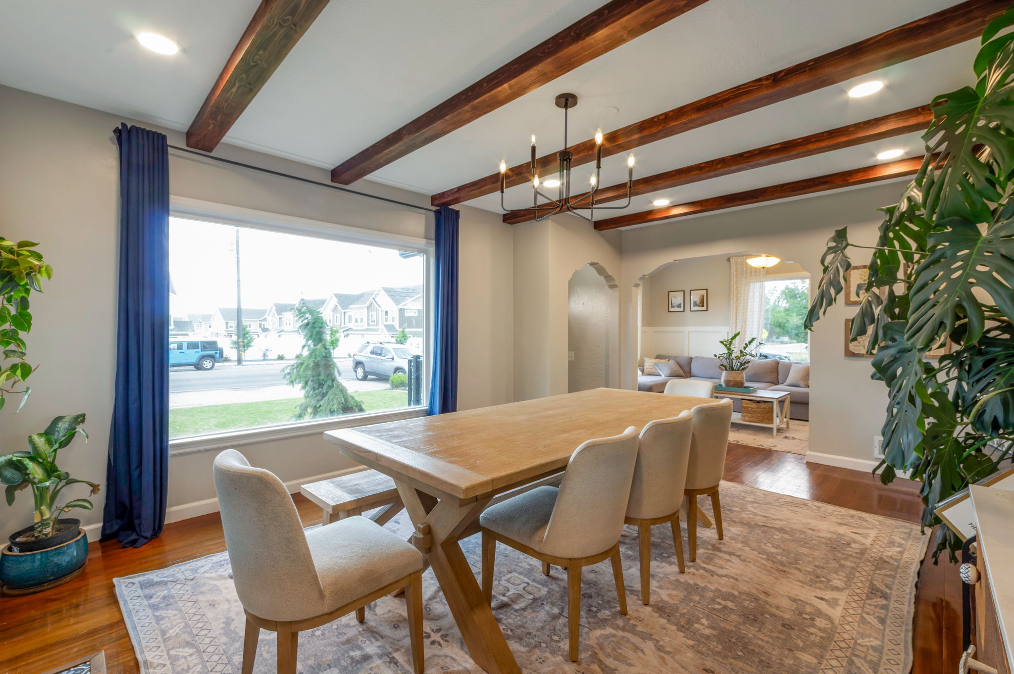 Dining area featuring a wide window, rich wood-finish flooring, recessed lighting, exposed ceiling beams, and arched doorways