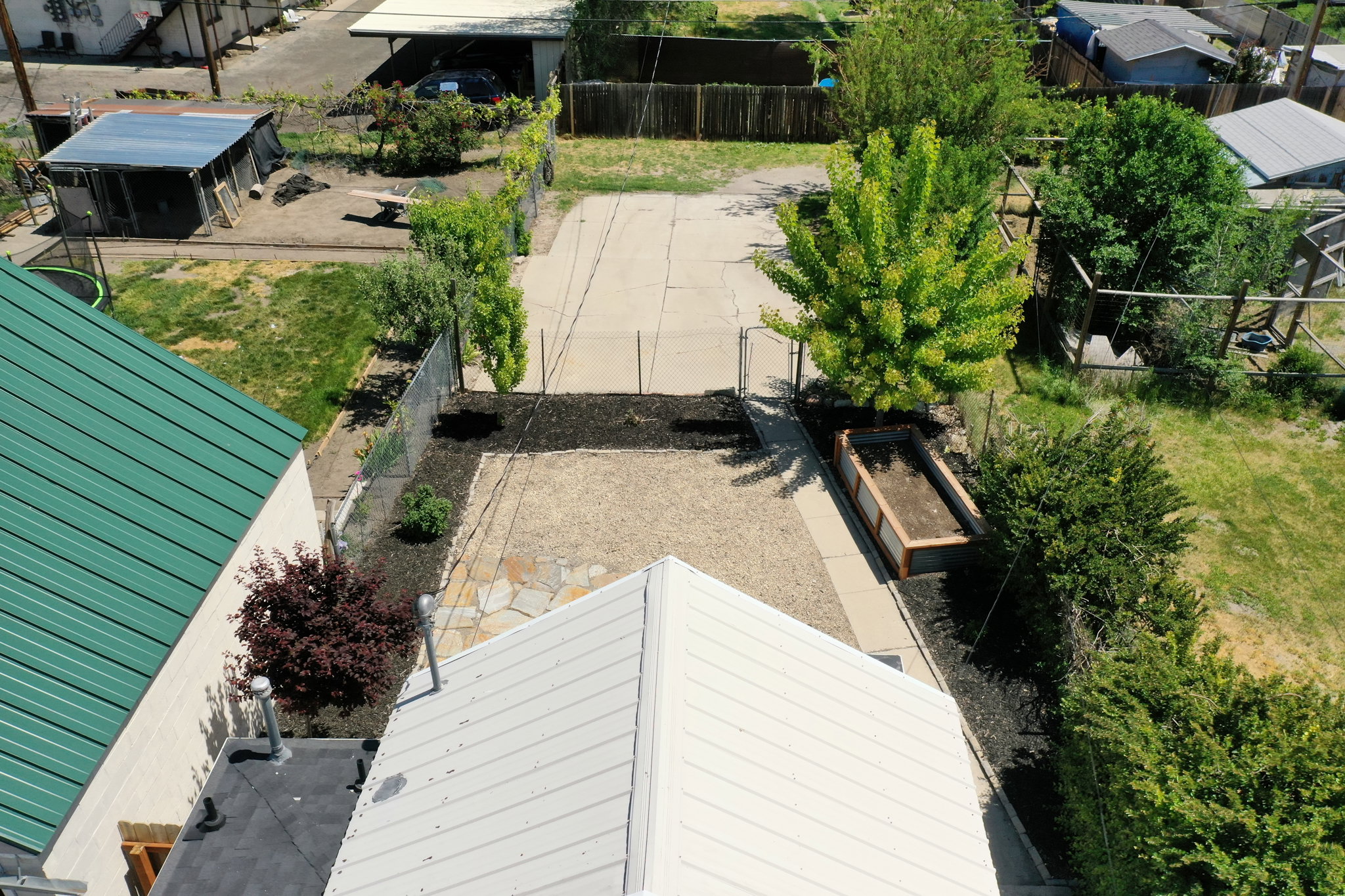 Expansive gravel patio area with flagstone accents, featuring a raised garden bed and mature landscaping