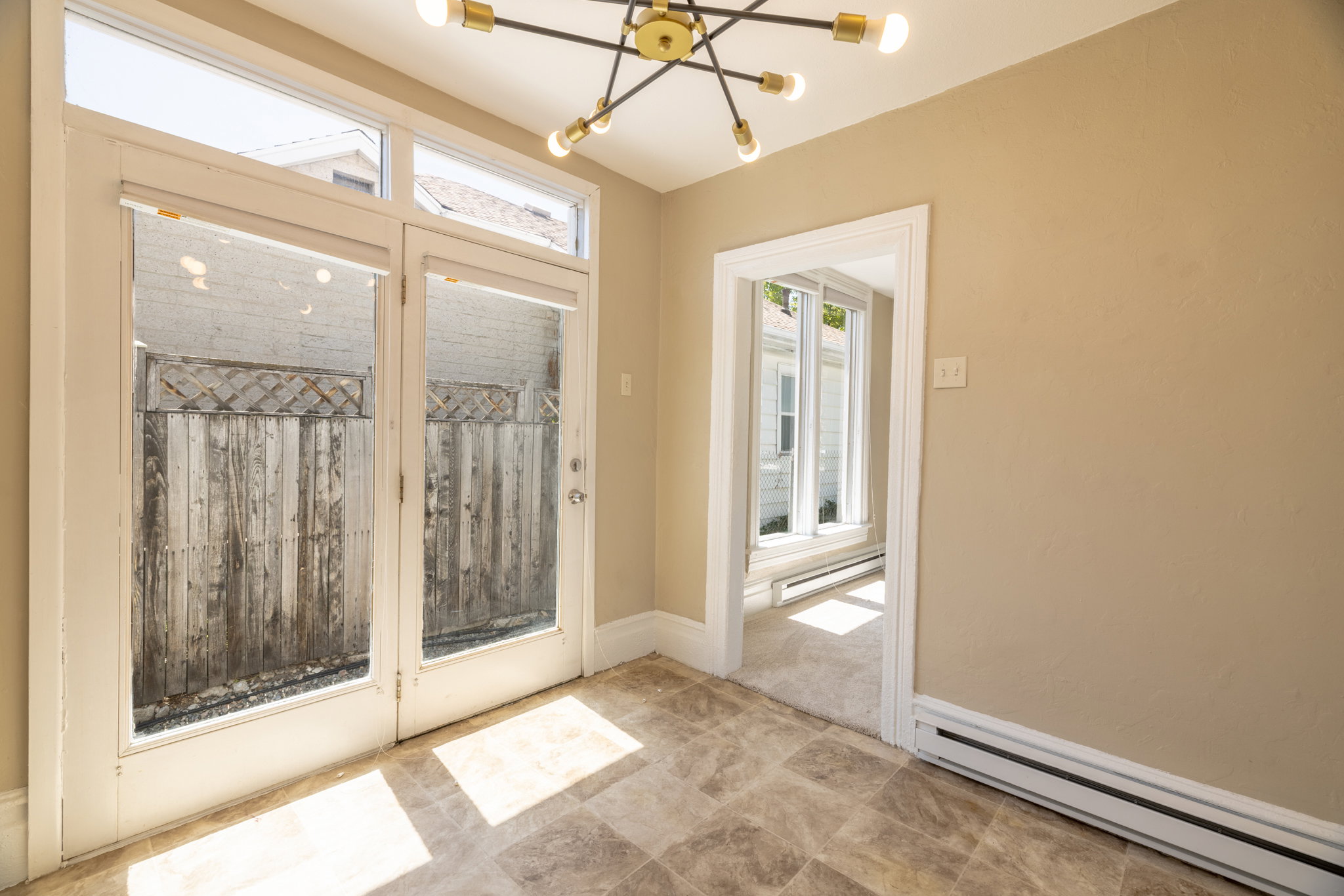 Room with tiled flooring, a modern chandelier, and double French doors with transom windows