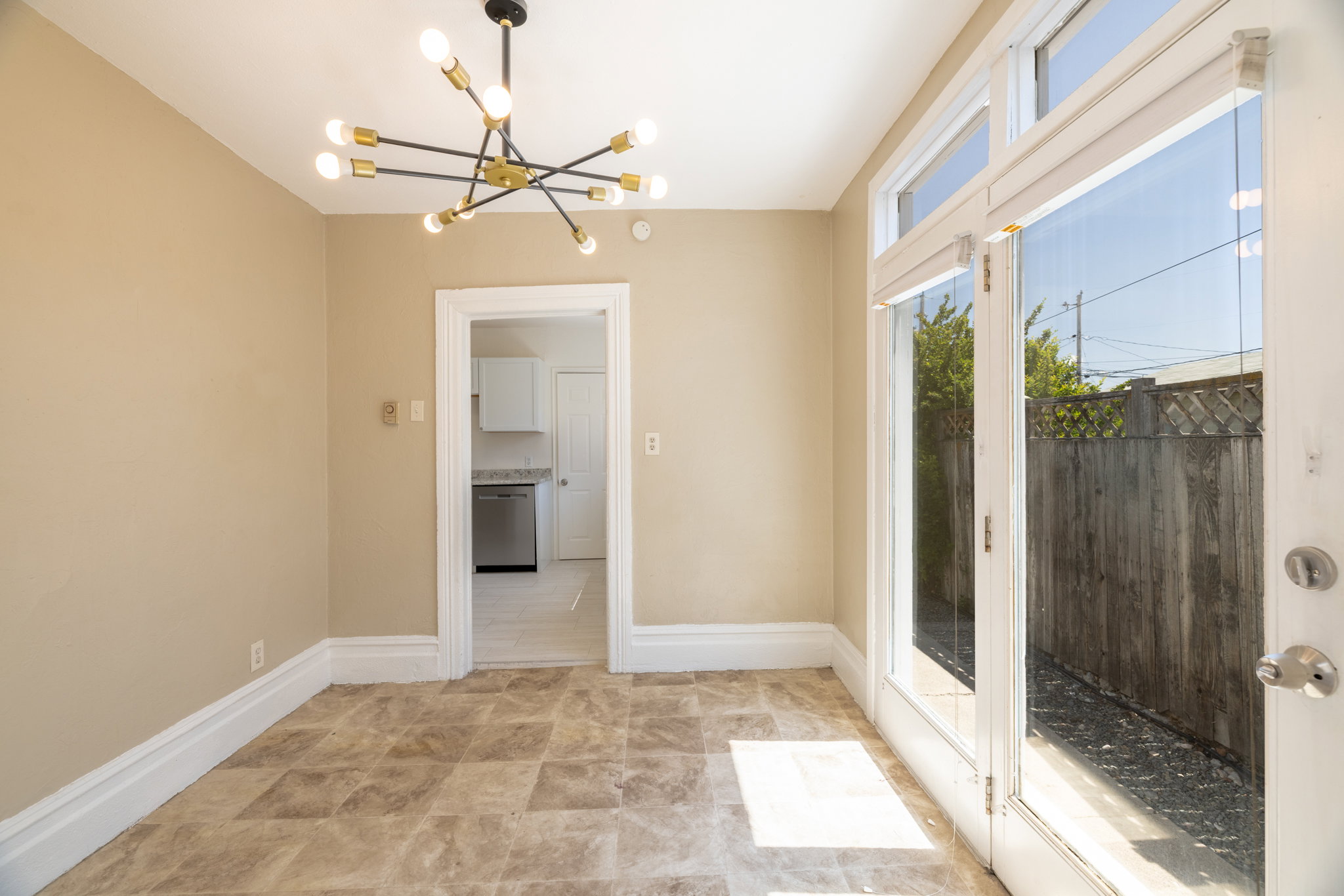 Neutral-toned room featuring patterned tile flooring, a modern sputnik chandelier, and white trim