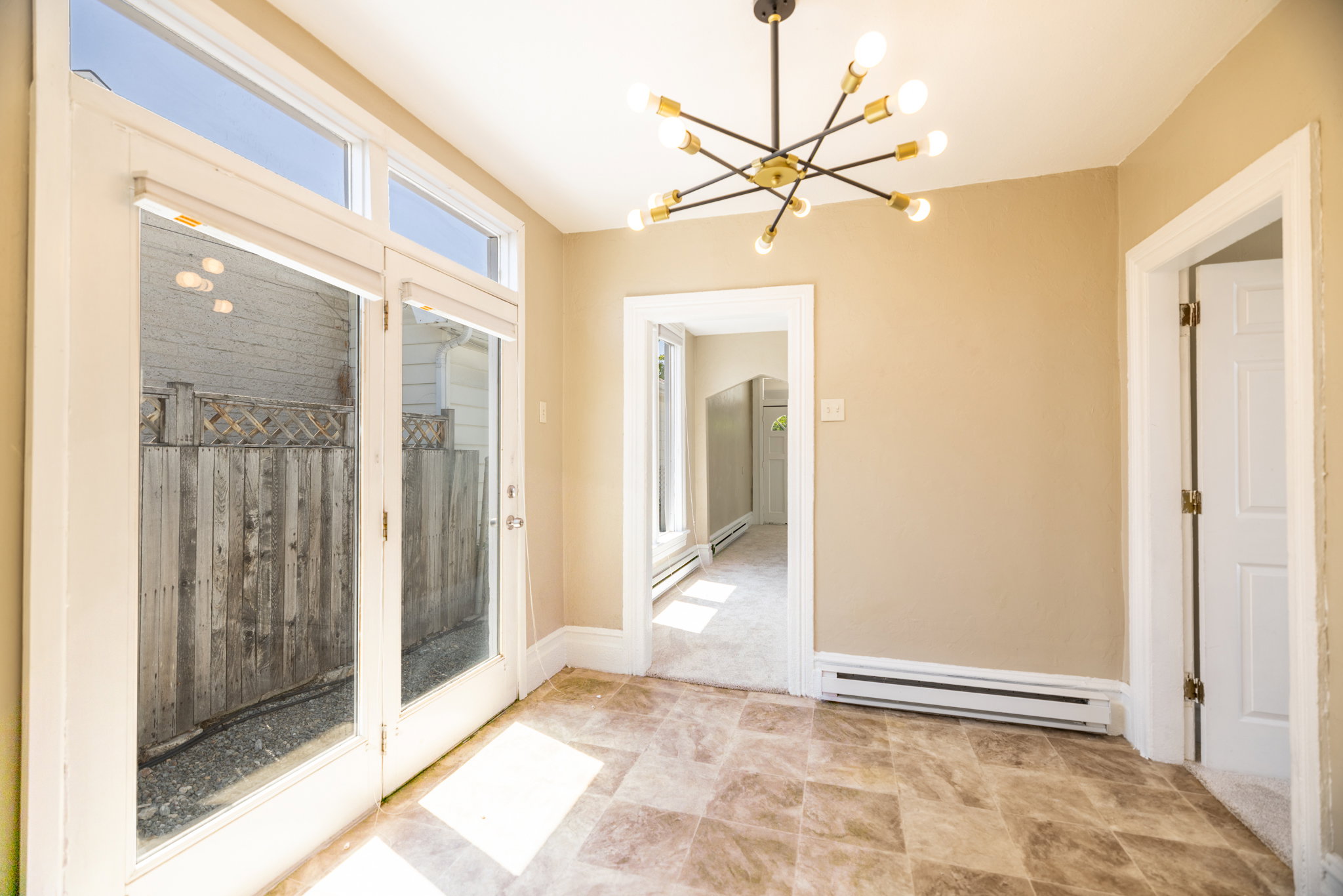 Spacious room featuring a contemporary sputnik chandelier, light tan wall paint, and durable patterned floor tiles