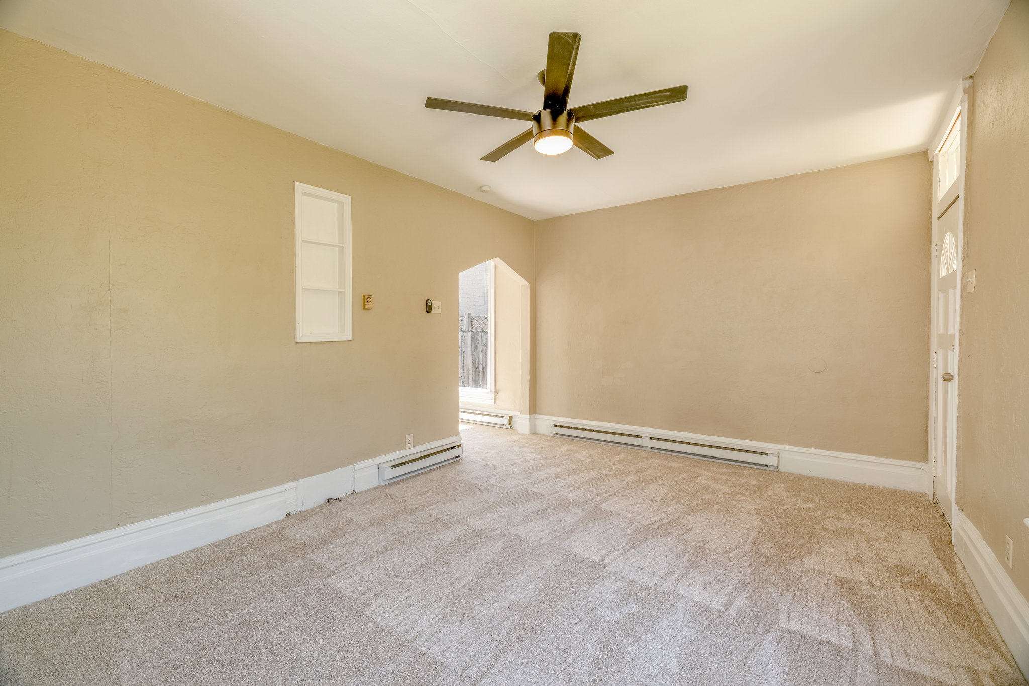 Neutral-toned carpeting and walls complement the ceiling fan with integrated lighting