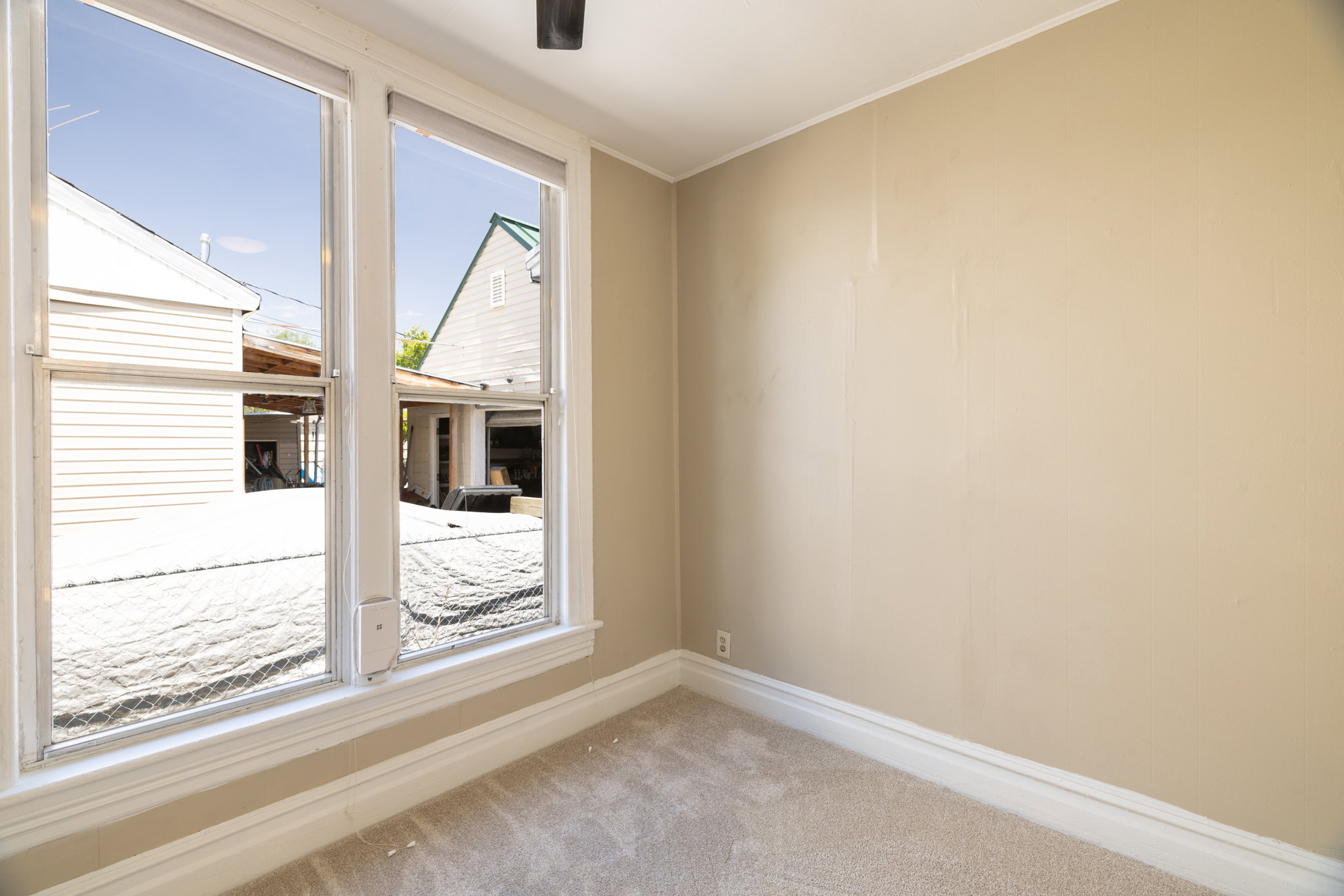 Double window framing an exterior, light beige wall color, white ceiling, white baseboards, and light carpet flooring