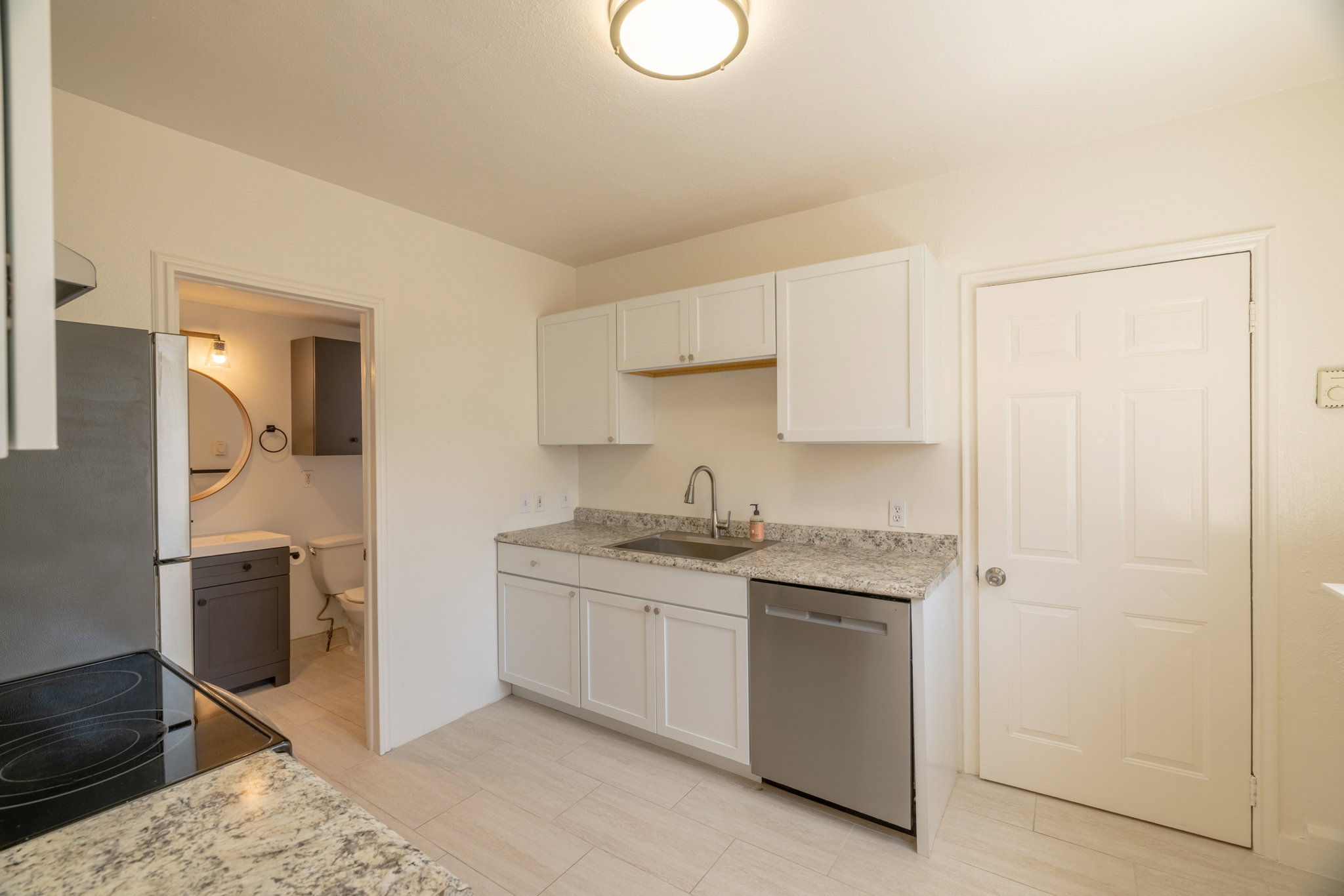 Kitchen featuring white shaker cabinetry, stainless steel dishwasher, speckled countertops, and a full-size refrigerator