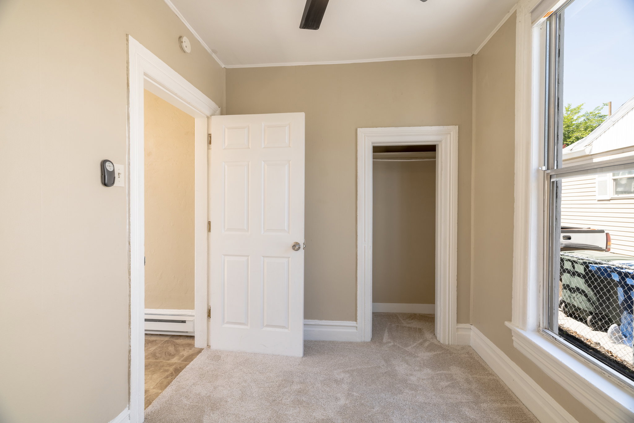 Neutral tone wall paint with white trim, light-colored carpet, and a window with natural light