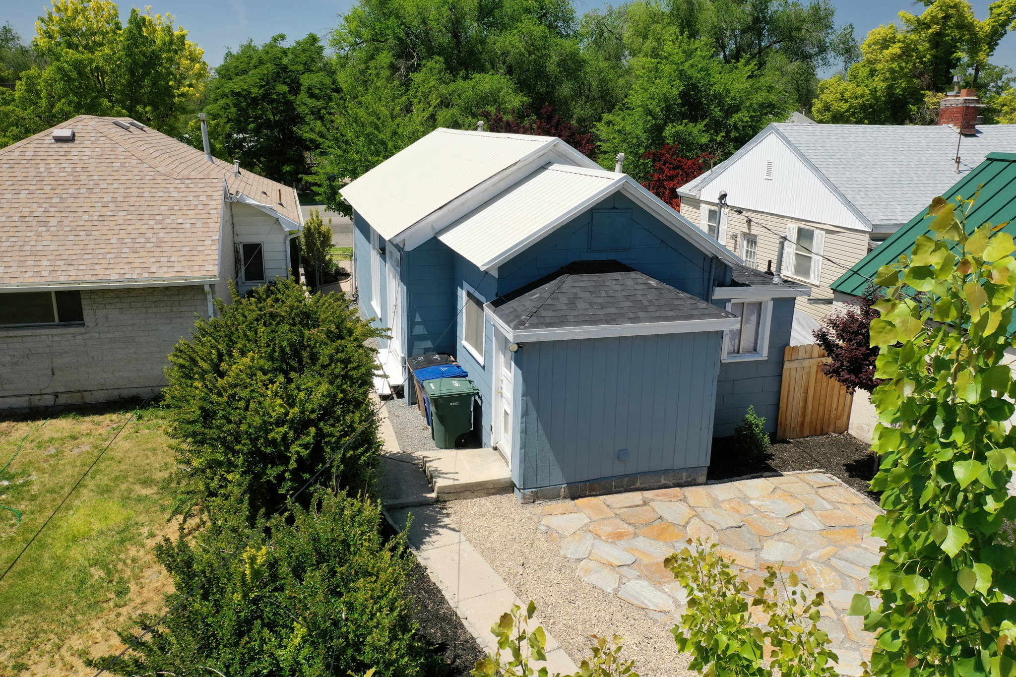 Blue exterior with white trim featuring a metal roof and a separate attached structure with a shingled roof