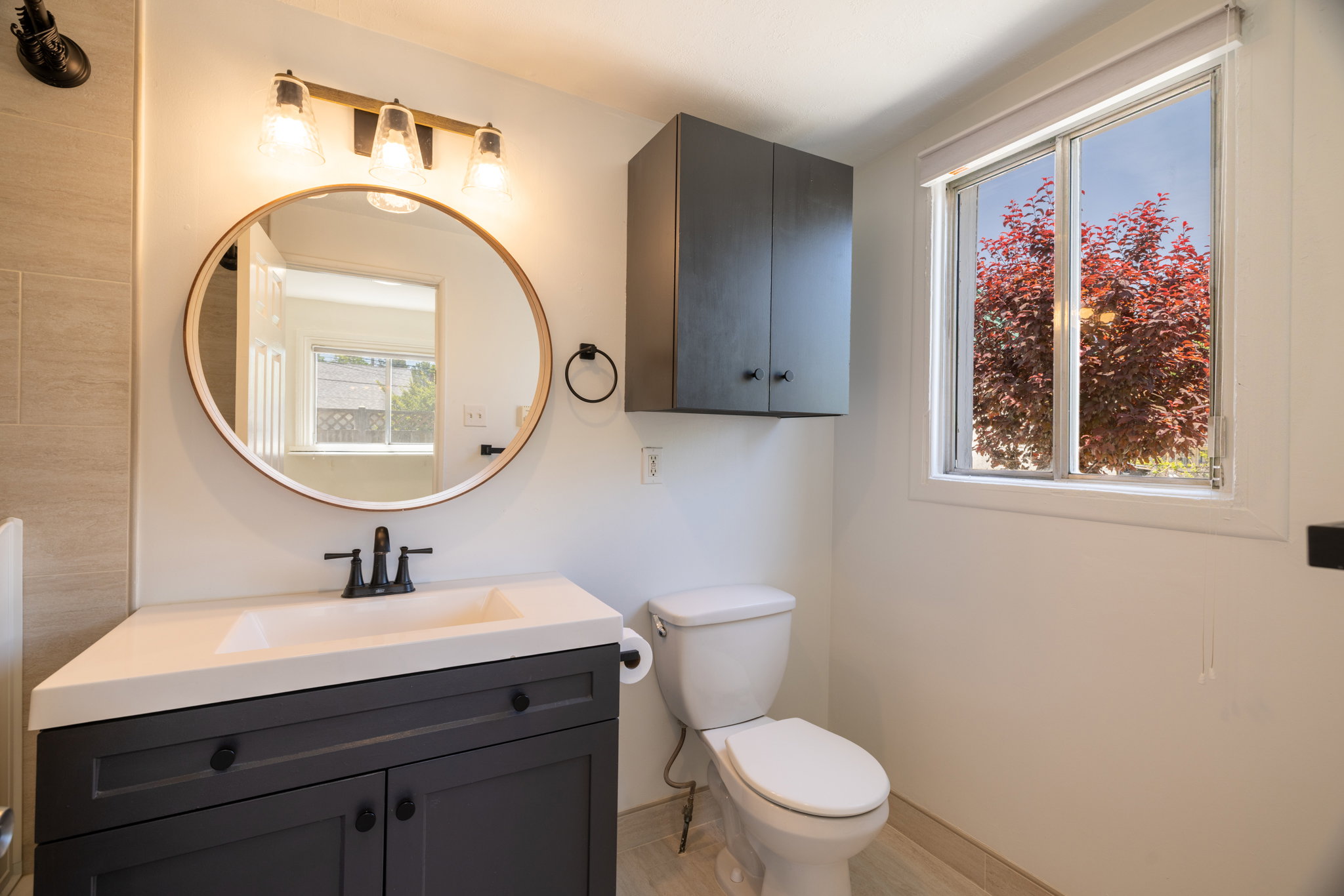 Bathroom featuring a modern vanity with integrated sink, circular mirror, and wall-mounted light fixture