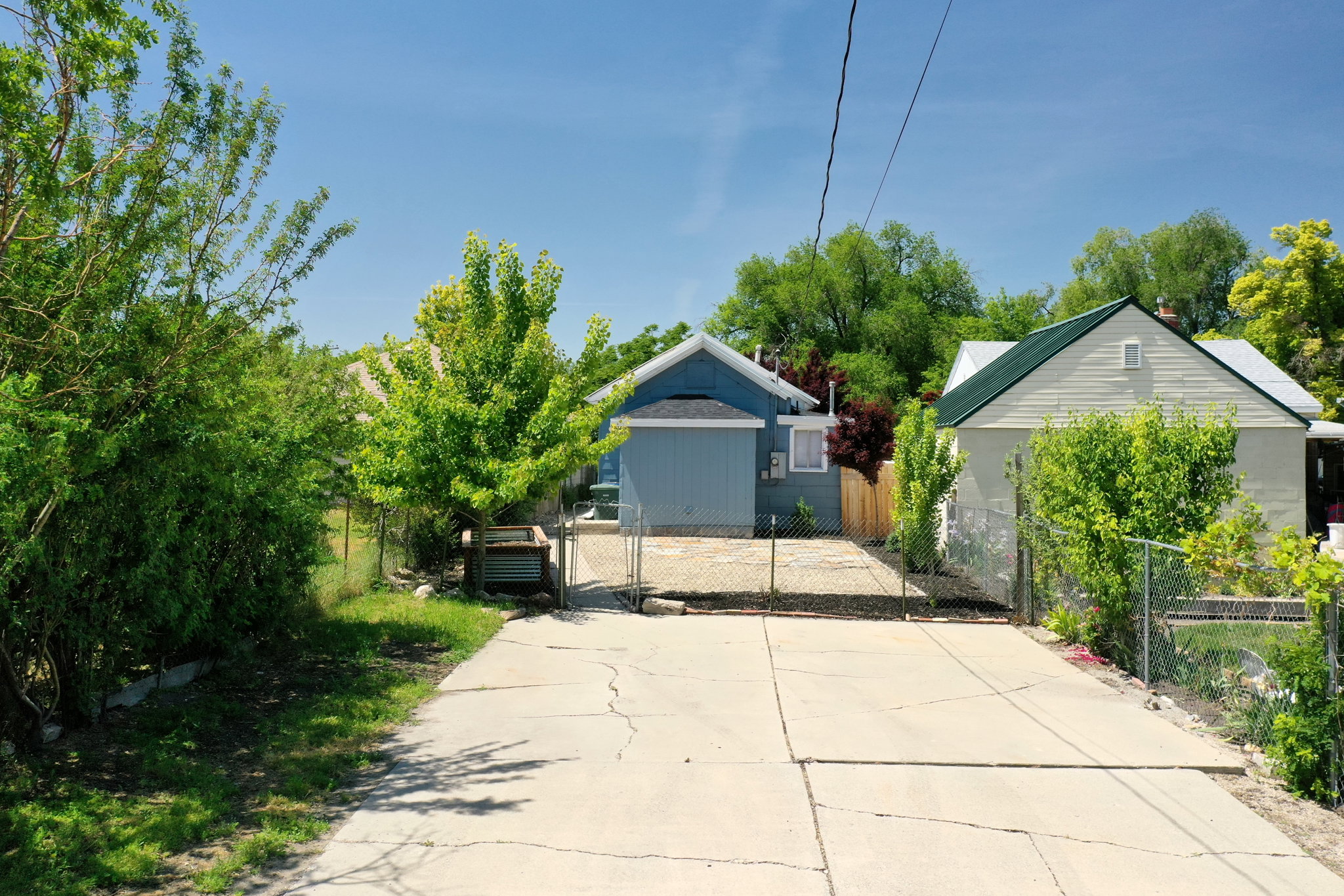 Concrete driveway providing access to a light blue dwelling with a dark blue gable roof and a white exterior dwelling with a green gable roof