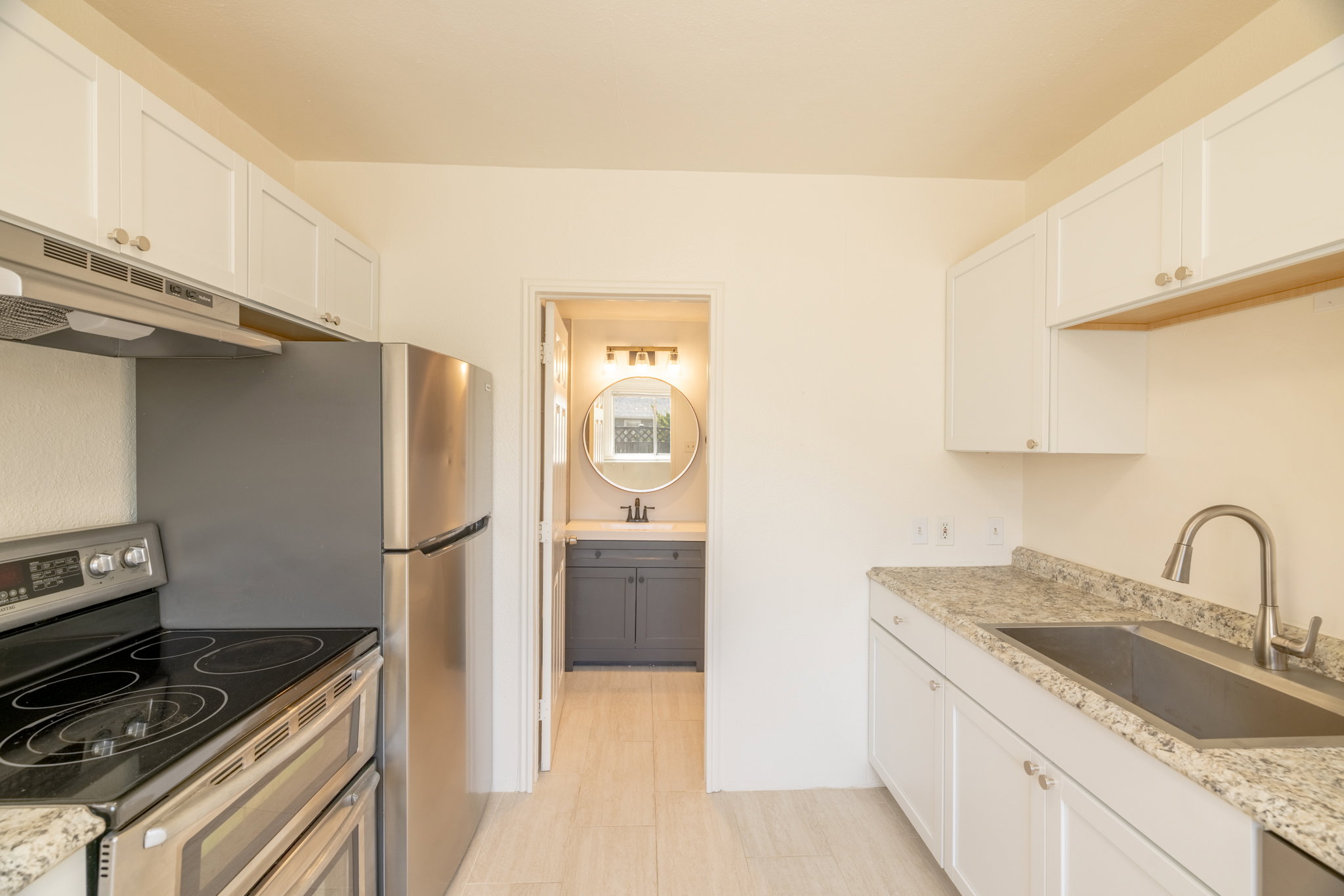 Kitchen featuring white cabinetry, light-toned countertops, stainless steel appliances, and a stainless steel sink with a gooseneck faucet