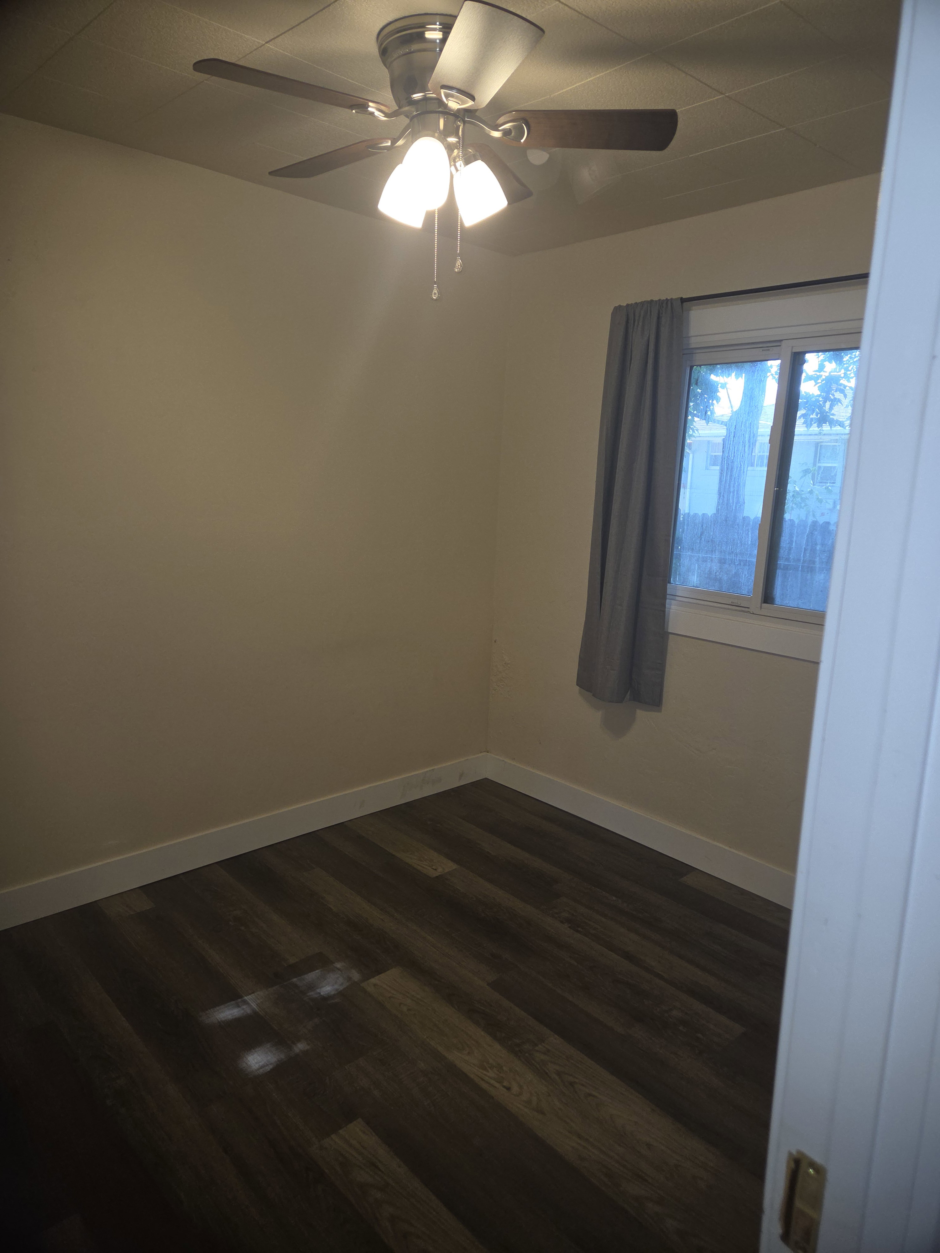Room featuring wood-finish flooring, light-toned walls, and white baseboards