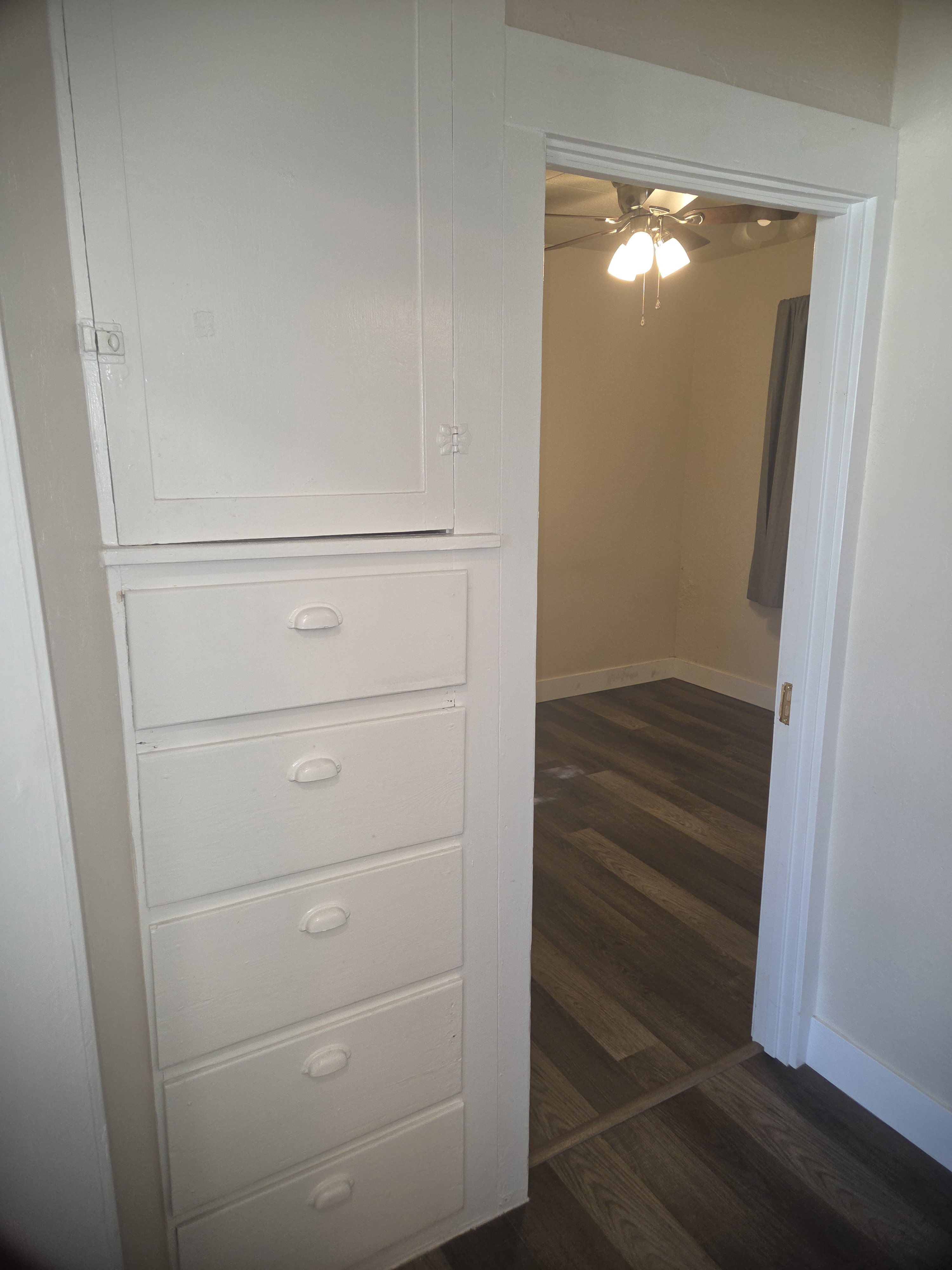 Built-in white cabinetry with five drawers and an upper storage cabinet