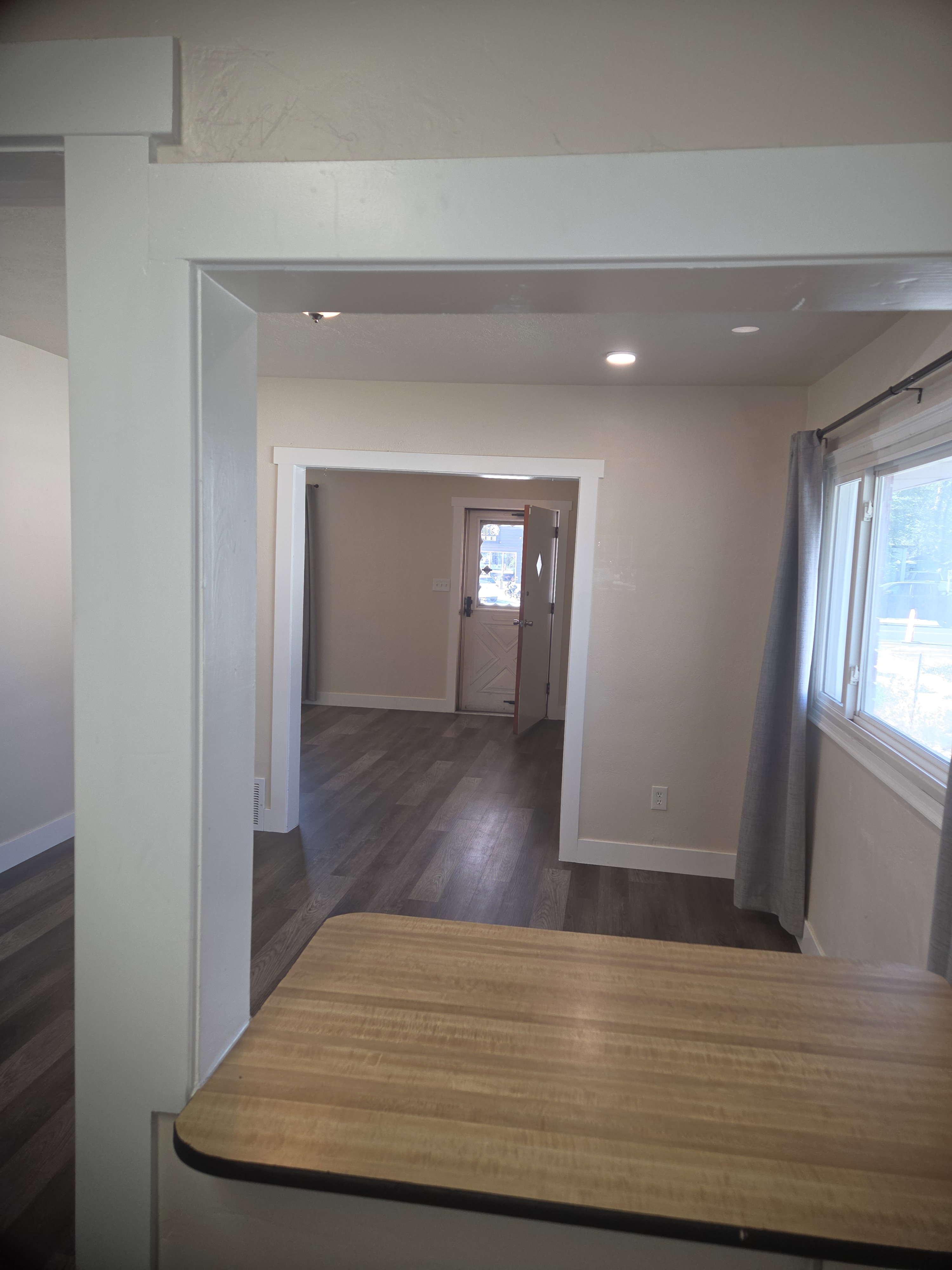 Interior architectural opening with white trim and recessed lighting, featuring wood-finish flooring and a light-toned countertop