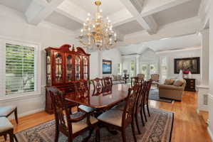 Dining area featuring a coffered ceiling, a brass chandelier, and wood-finish flooring