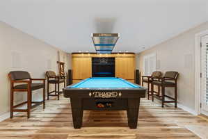 Recreation room featuring Diamond pool table with Littman lamp lighting, wood-finish flooring, and a built-in media center with surround sound