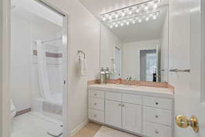 Bathroom featuring a vanity with a white countertop, integrated sink, and white cabinetry