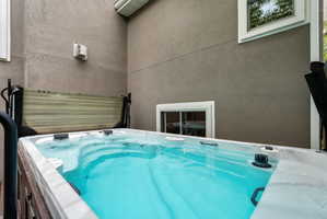 Arctic brand salt water outdoor swim spa with steps, set against a textured stucco exterior