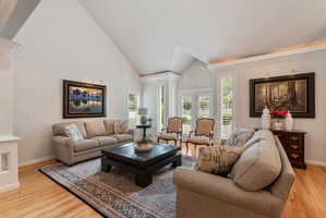 Living space featuring vaulted ceilings, wood-finish flooring,  and white plantation shutters